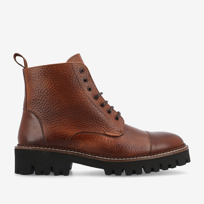 Brown leather lace-up ankle boot with a textured finish, black lug sole, and pull tab at the back.
