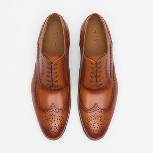 A pair of brown leather dress shoes with intricate brogue detailing and laces, viewed from above on a white background.