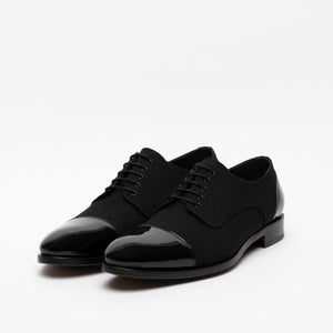 A pair of black men's dress shoes with a polished cap toe design and lace-up closure, displayed on a white background.