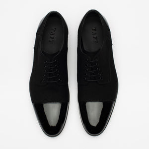 A pair of black dress shoes with glossy toe caps and the brand name TAFT visible inside.