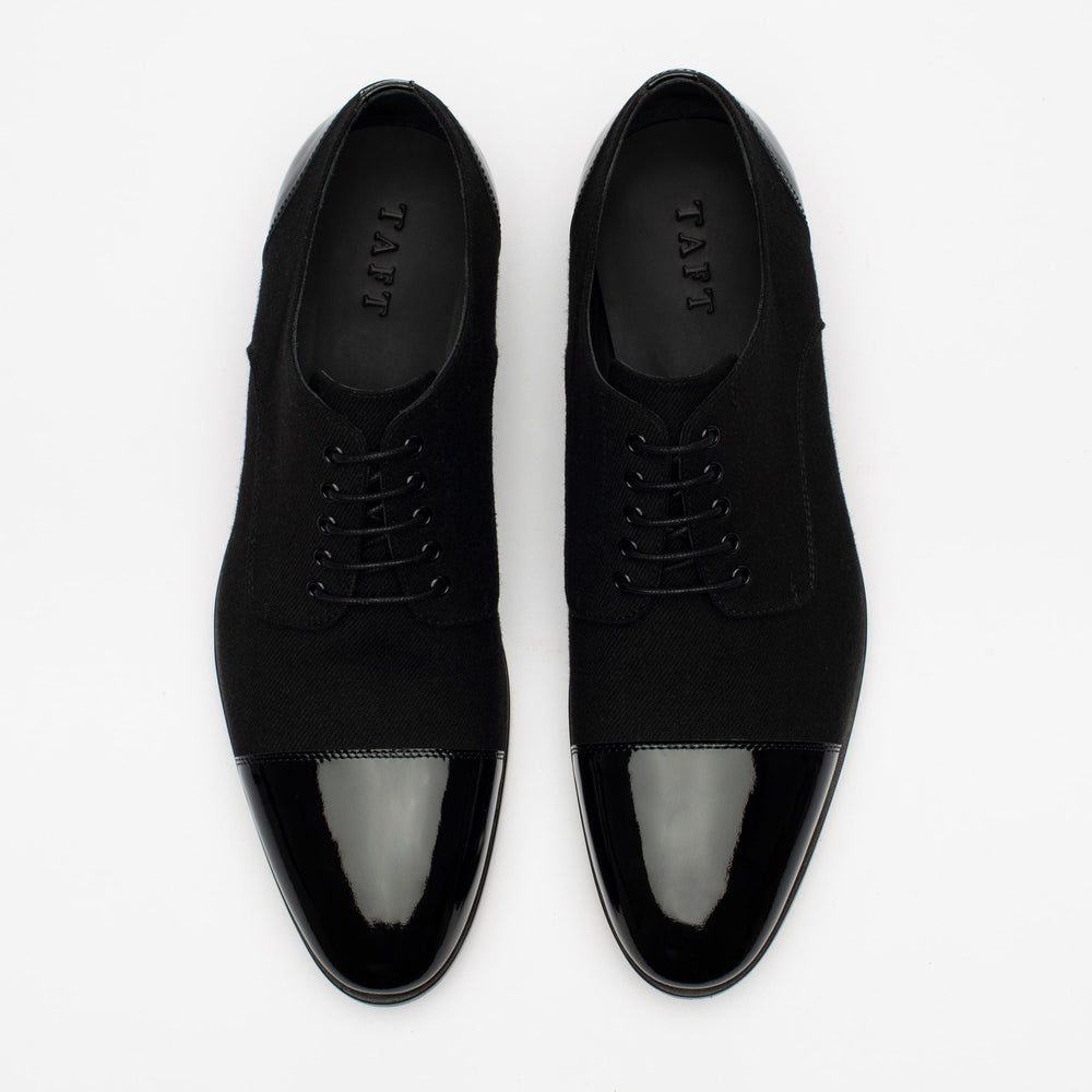 A pair of black dress shoes with glossy toe caps and the brand name TAFT visible inside.