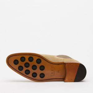A single beige and brown shoe lies on its side, showcasing the sole with eleven black circular grips and the brand name TAFT imprinted.