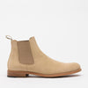 Beige suede Chelsea boot with elastic side panels and a pull tab at the back. The boot features a brown sole with a slight heel.
